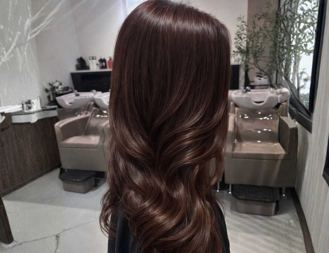 Long, wavy brown hair styled in a modern salon setting.